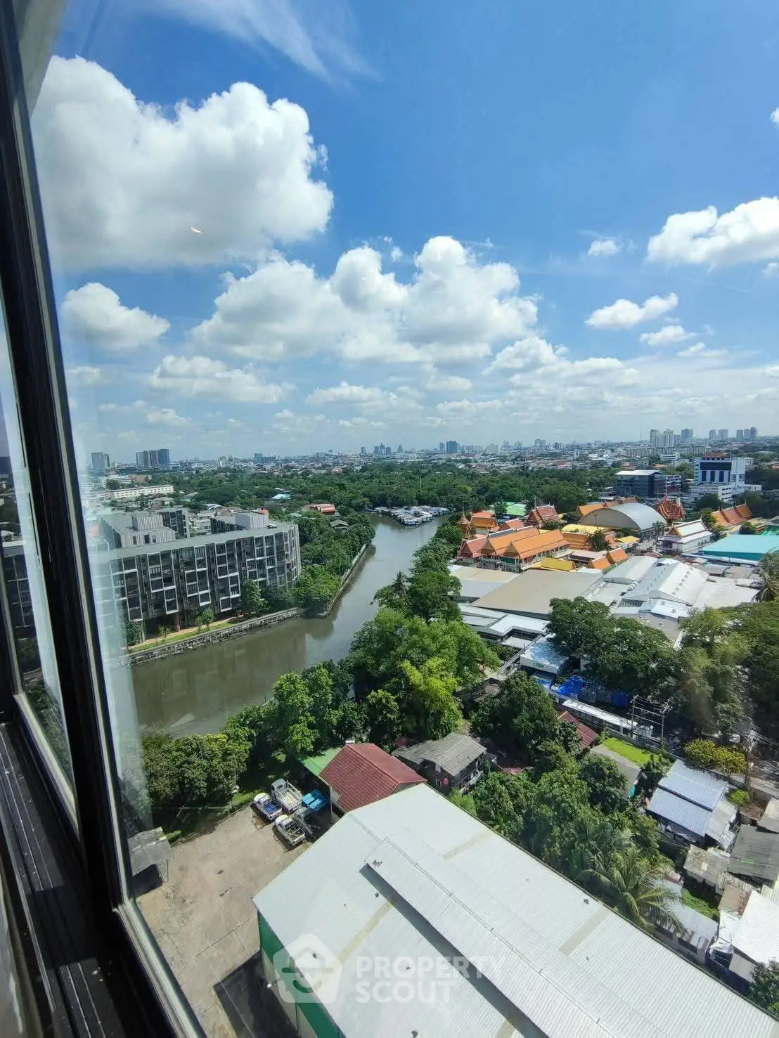 Stunning cityscape view from high-rise window overlooking river and urban landscape under blue sky.