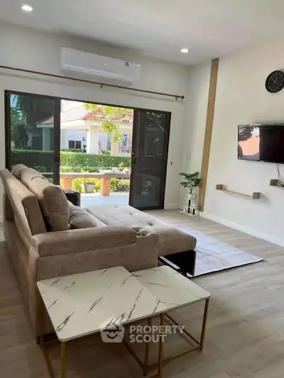 Spacious living room with modern decor and large windows offering garden views.