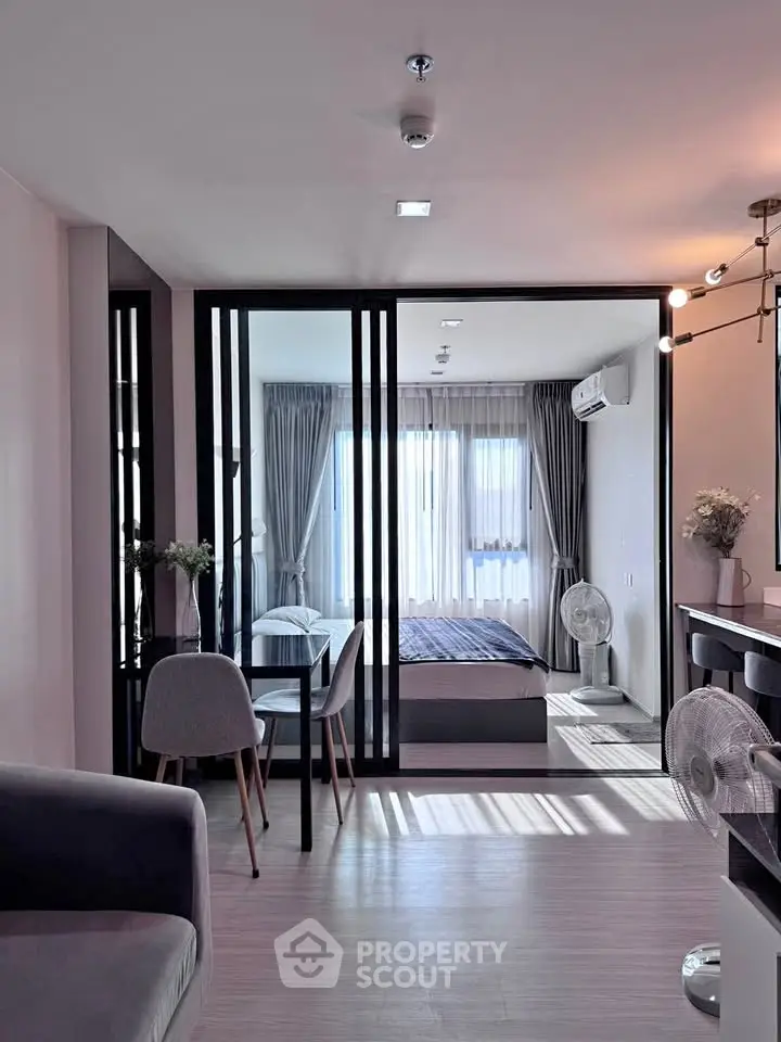 Modern apartment interior with open layout, featuring a stylish living area and bedroom with large windows.