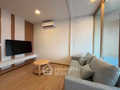 Modern living room with sleek design, featuring a wall-mounted TV, air conditioning, and a comfortable sofa.
