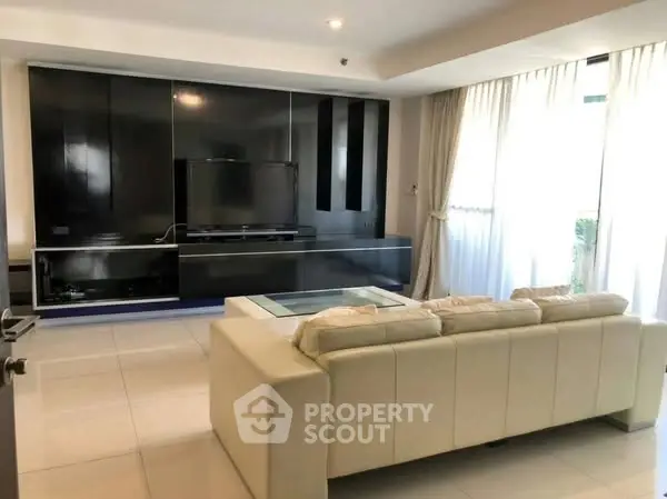 Spacious modern living room with sleek black entertainment center and plush white sofa.