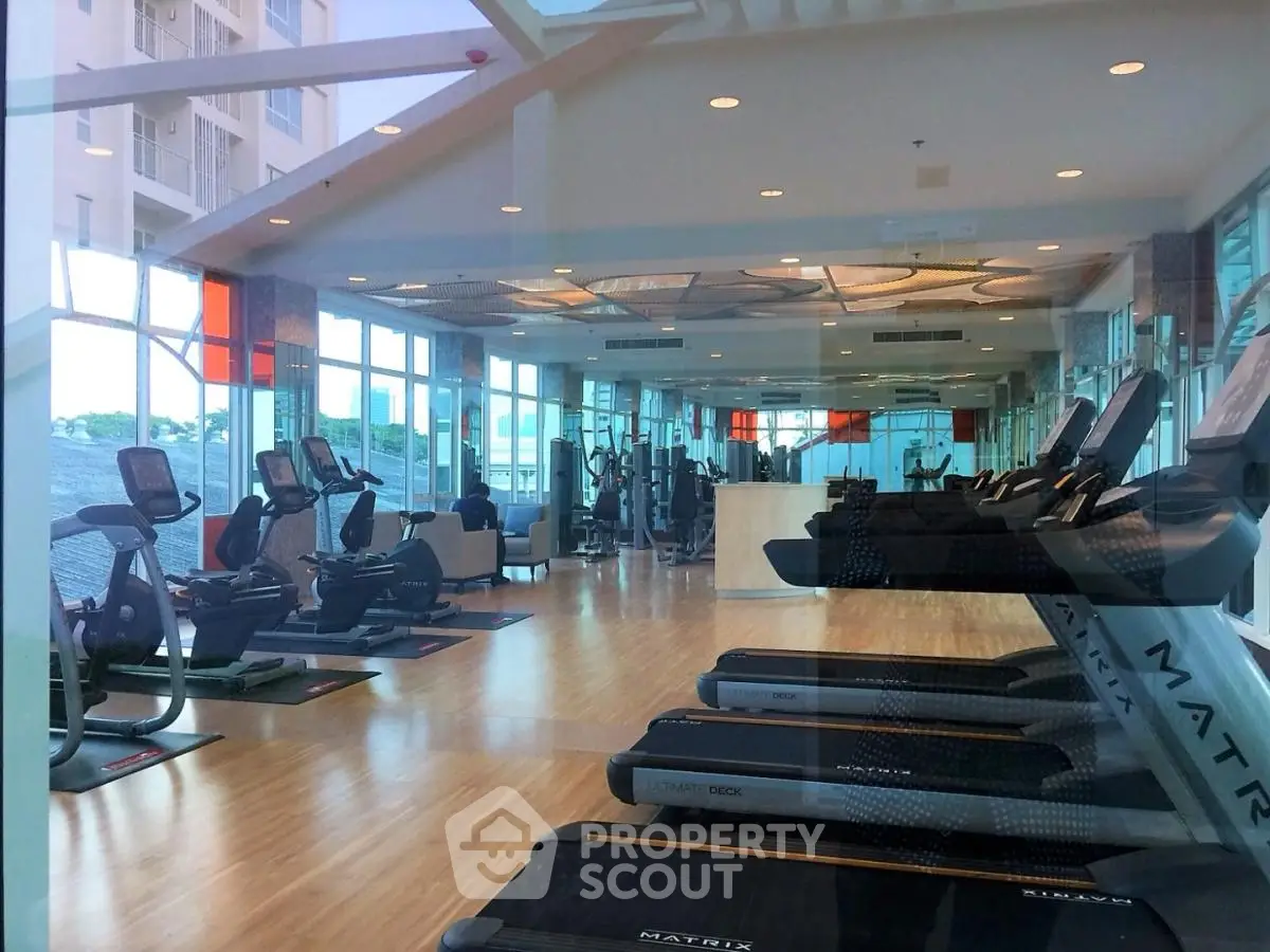 Spacious modern gym with state-of-the-art equipment and large windows offering natural light.