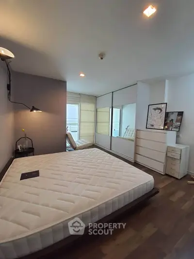 Spacious bedroom with modern decor and large windows for natural light.