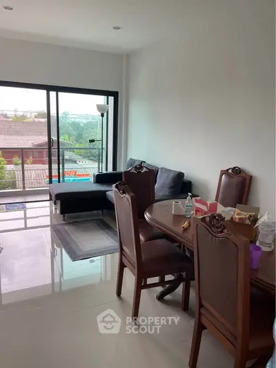 Spacious living room with elegant dining set and cozy sofa, featuring large windows for natural light.