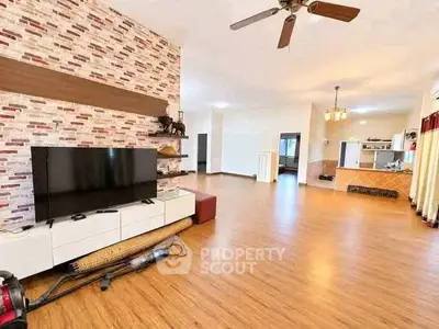 Spacious living room with modern decor and open layout, featuring wooden flooring and stylish ceiling fan.