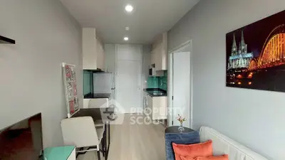 Modern living room with stylish decor and compact kitchen in open layout apartment.