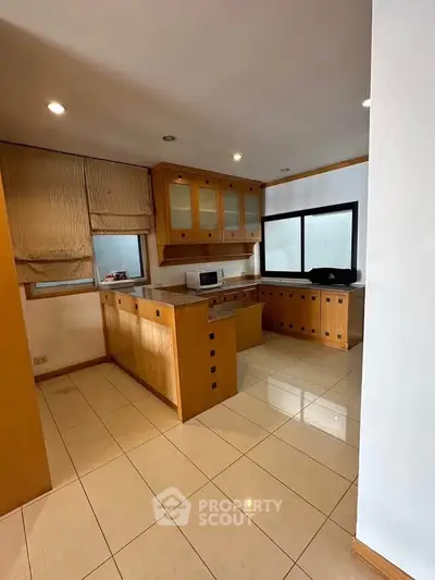 Spacious kitchen with wooden cabinets and modern appliances in a bright, open layout.