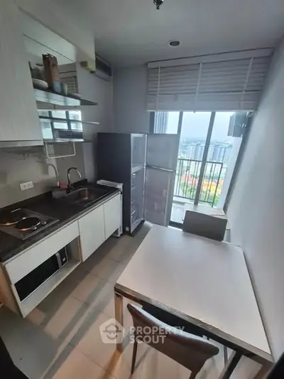 Modern compact kitchen with dining area and city view from balcony.