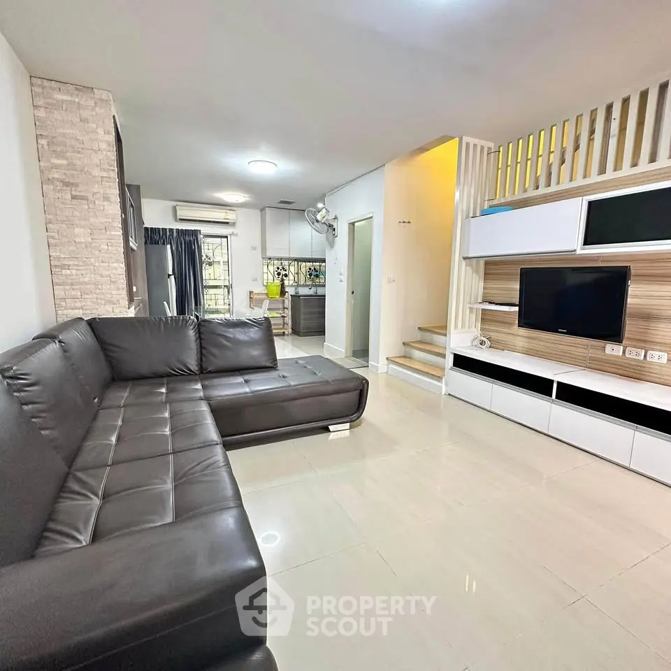 Modern living room with sleek black leather sofa and stylish entertainment unit