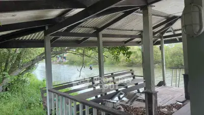 Charming riverside deck with rustic wooden seating and lush greenery, perfect for serene outdoor relaxation.
