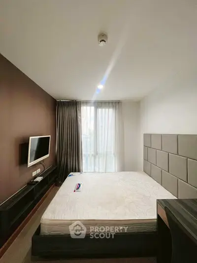 Modern bedroom with wall-mounted TV and large window for natural light.