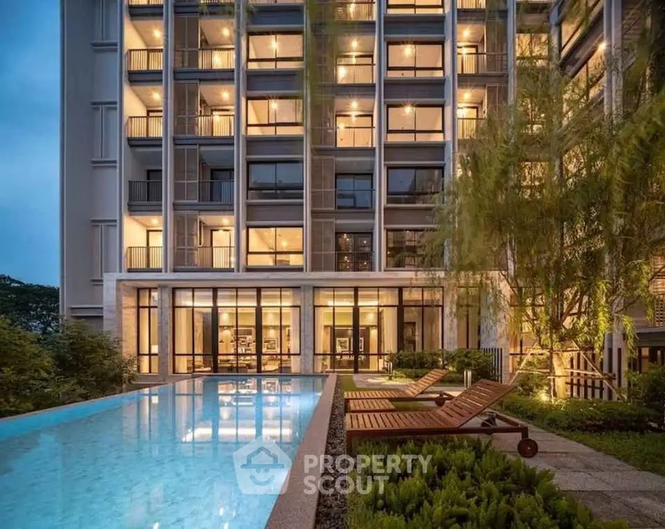 Luxurious modern apartment building with pool and garden view at dusk.