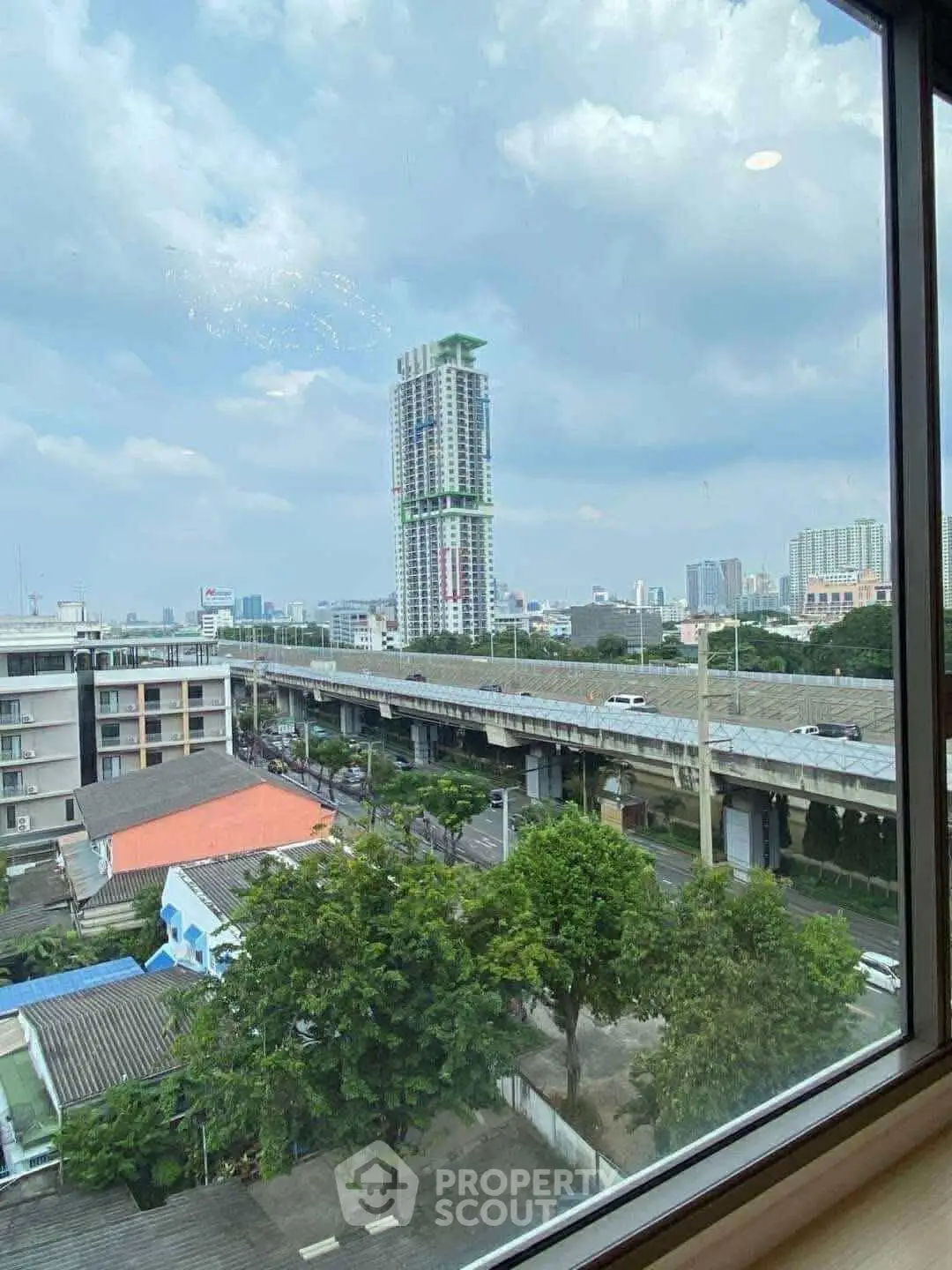 Stunning cityscape view from a high-rise window showcasing urban skyline and elevated road.