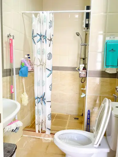 Cozy bathroom with shower, modern fixtures, and nautical-themed curtain in a well-lit space.