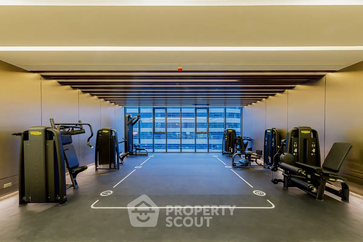 Modern gym with state-of-the-art equipment and large windows offering city views.