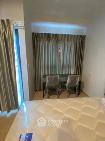 Cozy bedroom with elegant curtains and a small study area, perfect for relaxation and work.