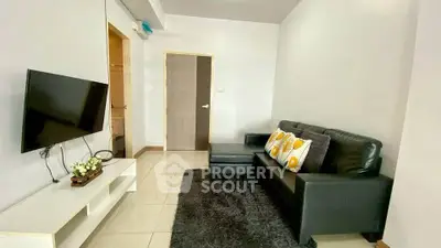 Modern living room with sleek black sofa and wall-mounted TV in a cozy apartment.
