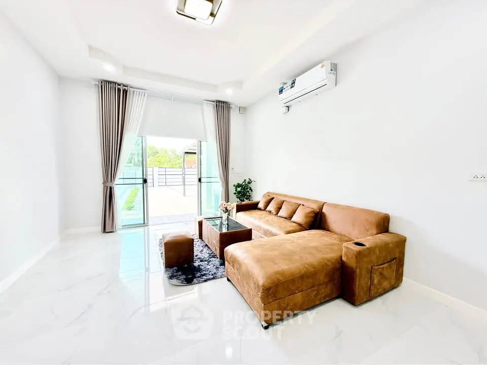 Spacious modern living room with stylish brown leather sofa and large windows for natural light.