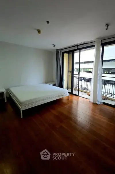 Spacious bedroom with large windows and balcony access in modern apartment.