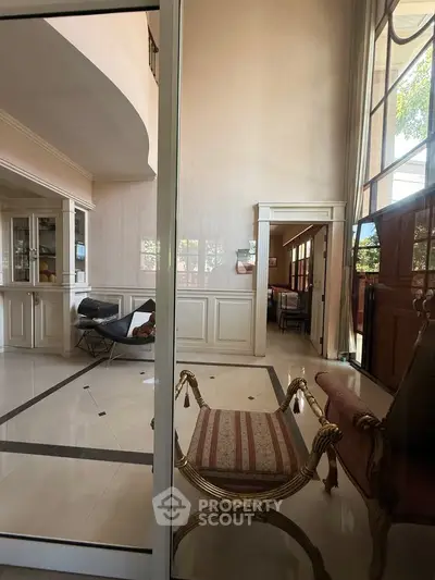 Luxurious living room with high ceilings and elegant furniture, featuring large windows for natural light.