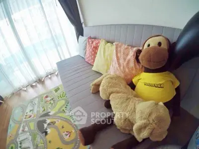 Cozy living room with plush toys and colorful cushions on a modern sofa, bright natural light through sheer curtains.