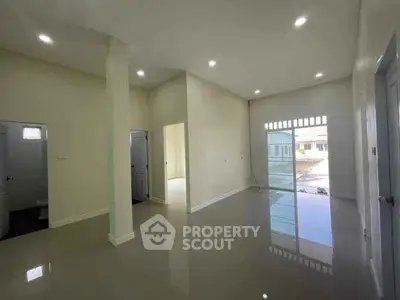 Spacious modern living room with high ceilings and glossy floors, featuring ample natural light and open layout.