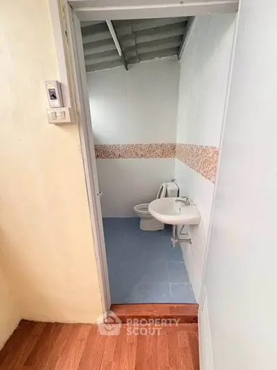 Compact bathroom with modern fixtures and tiled walls, featuring a toilet and sink.