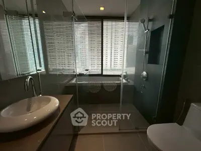 Modern bathroom with glass shower, bathtub, and sleek fixtures in a high-rise apartment.