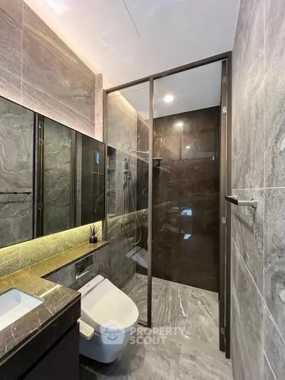 Luxurious modern bathroom with sleek marble finishes and glass shower enclosure.