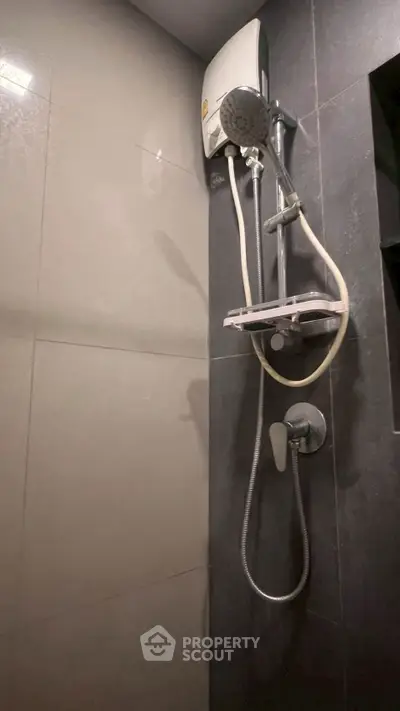 Modern bathroom with sleek shower fixtures and dark tile design.