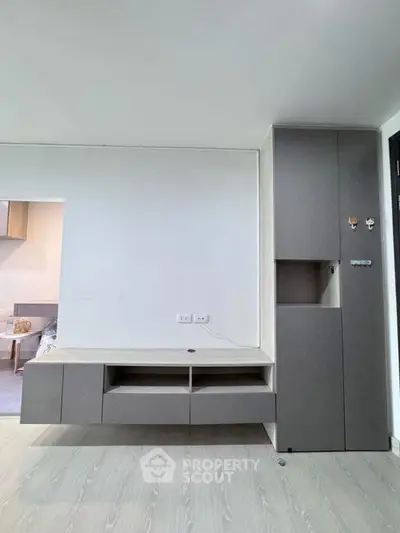 Modern minimalist living room with sleek storage cabinets and light wood flooring.