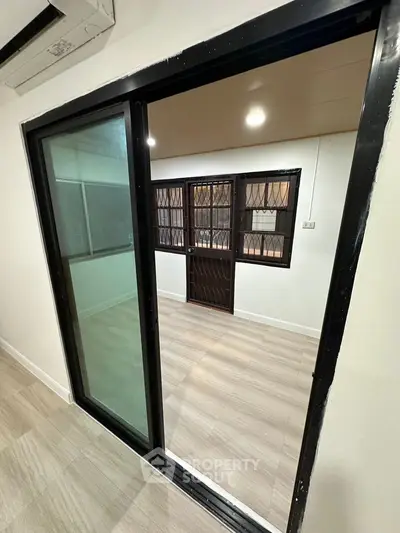 Modern interior with sliding glass door and secure window bars, featuring sleek flooring.