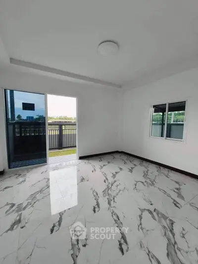 Spacious room with marble flooring and balcony access in modern apartment.