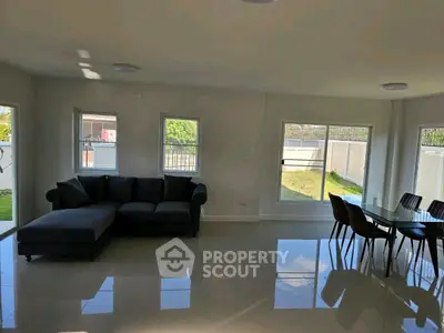 Spacious living room with modern furniture and large windows overlooking a garden.