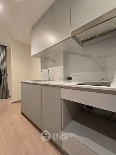 Modern kitchen with sleek cabinetry and marble backsplash in a contemporary apartment.