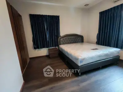 Spacious bedroom with elegant dark wood flooring and stylish bed frame, perfect for a cozy retreat.