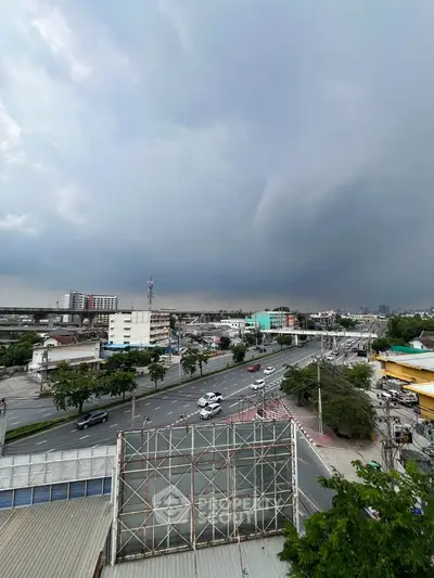 Panoramic cityscape view with dramatic cloudy sky and busy roads.