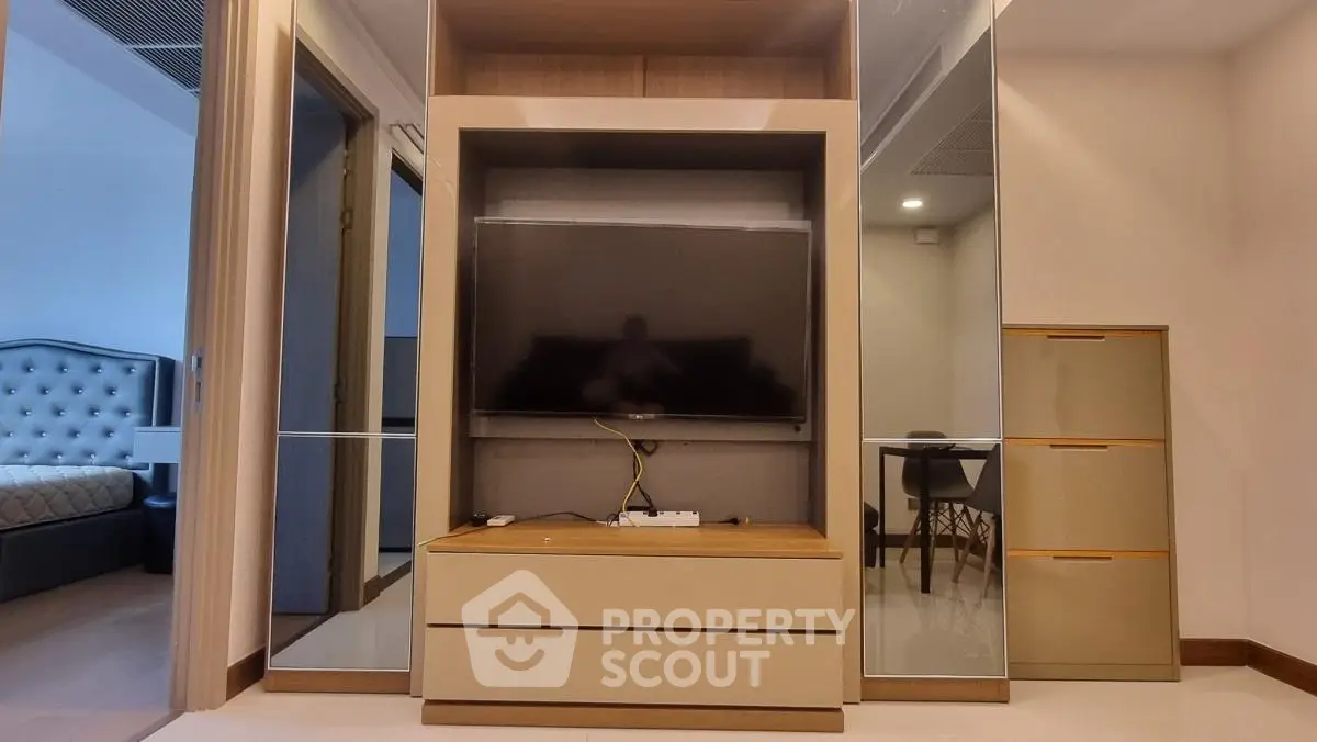 Modern living room with sleek TV unit and mirrored storage in stylish apartment.