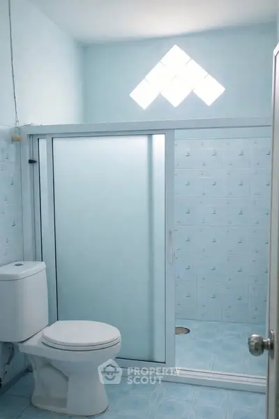 Bright bathroom with frosted glass shower and geometric window design.