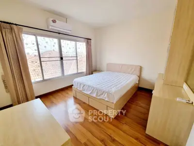 Bright and cozy bedroom with wooden flooring and large window view.