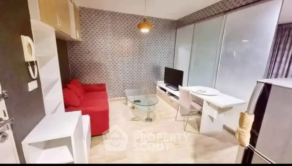Modern living room with red sofa, glass coffee table, and TV in stylish apartment.
