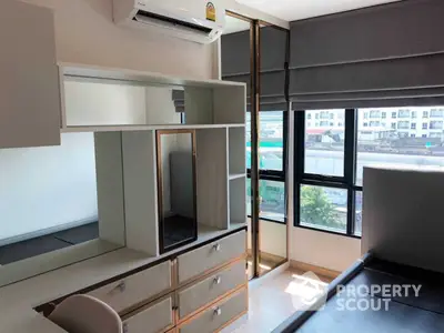 Modern studio apartment with sleek built-in furniture, ample natural light, and a city view through large windows, perfect for urban living.