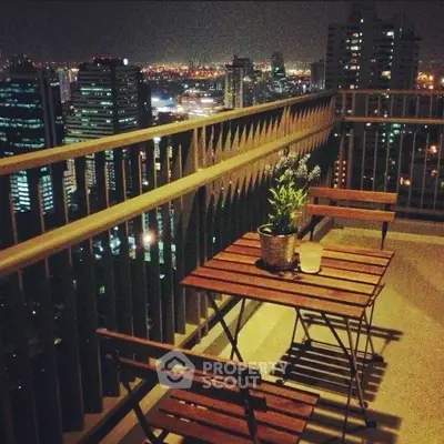Stunning cityscape view from a high-rise balcony with cozy seating.