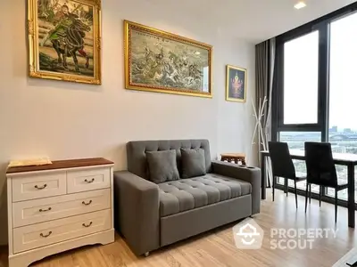 Elegant living room with plush grey sofa, classic artwork, and a panoramic city view through floor-to-ceiling windows, exuding modern sophistication.