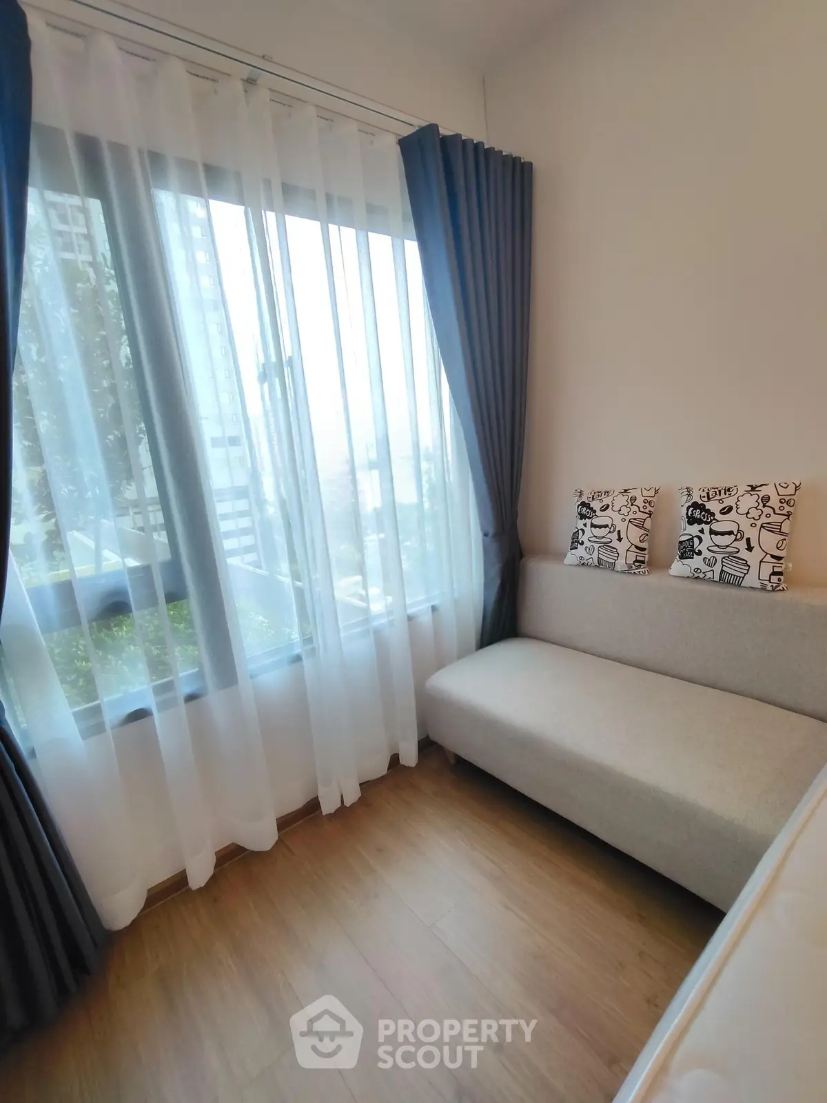 Cozy corner unit with large window and stylish sofa, offering a serene view and abundant natural light.
