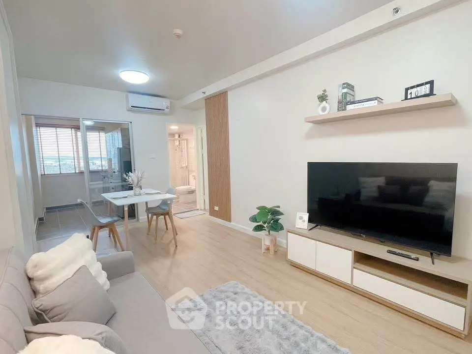 Modern living room with stylish decor and large TV, open layout leading to dining area.