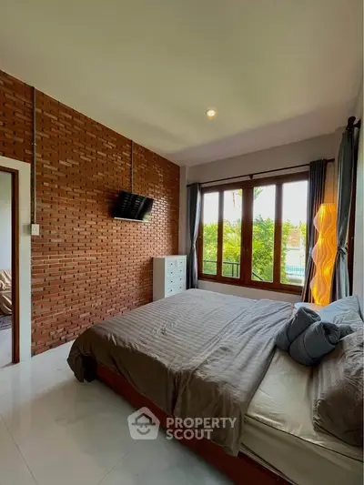 Charming bedroom with exposed brick wall and large window overlooking greenery.