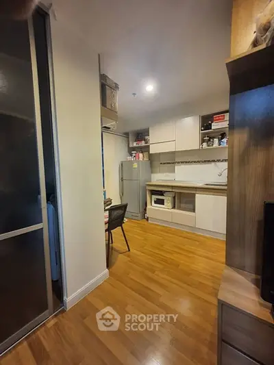 Modern kitchen with wooden flooring and sleek cabinetry in a cozy apartment setting.