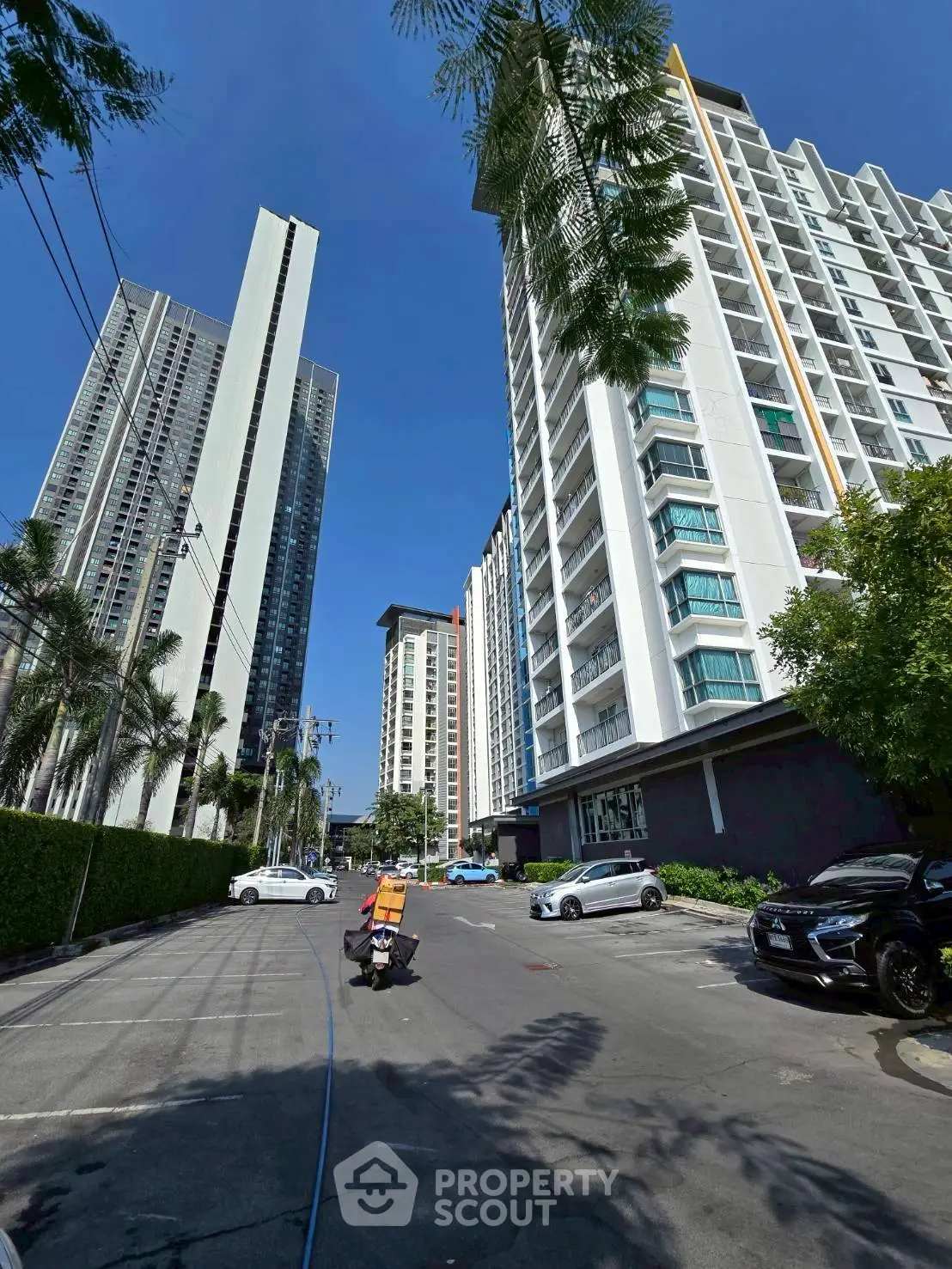 Modern high-rise residential buildings with clear blue sky and parked cars