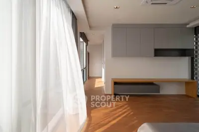 Spacious modern living area with wooden flooring and large windows for natural light.